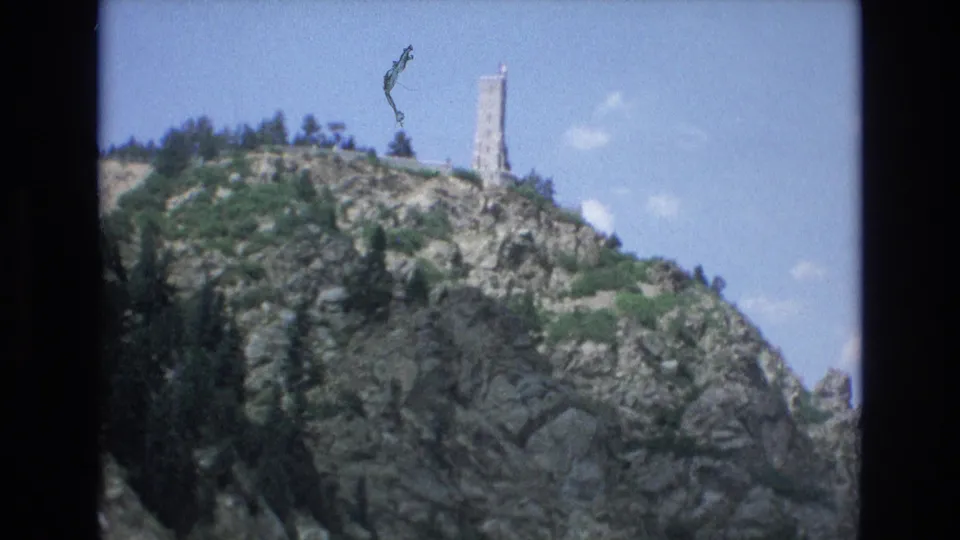 A brief exterior view shows a rocky Colorado Springs hillside with a tall tower-like structure and blue sky, following the bird enclosure shots.