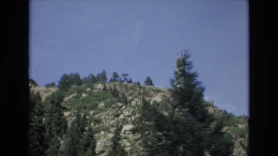 Colorado Springs home-movie frame with the rocky slope filling the view and the stone tower partly near the upper right edge.