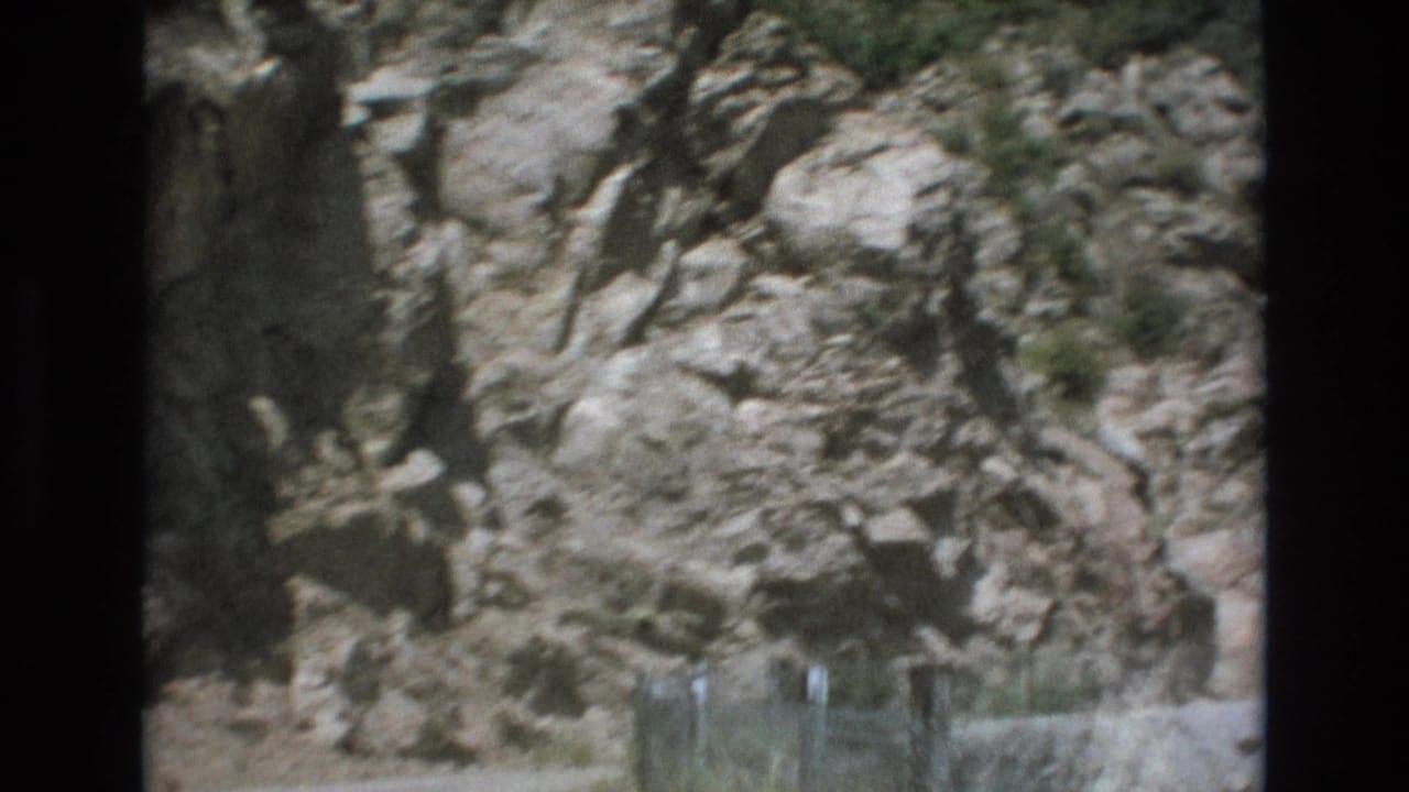 Close roadside view of rough rock and guard fencing.