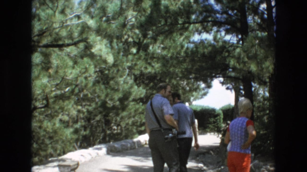 Three tourists continue down a shaded park path.