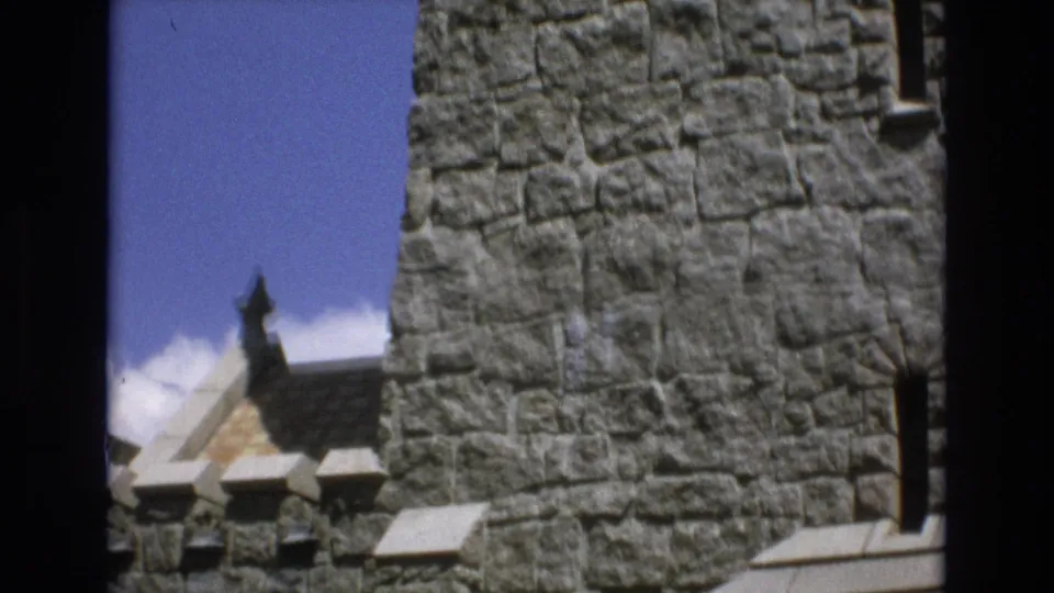 1973 Colorado Springs 8mm frame showing stone wall sections, narrow window openings, battlement-like trim, and part of a small roofline between the masonry.