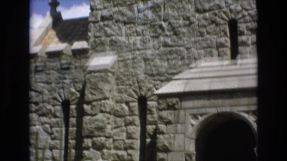1973 Colorado Springs 8mm frame showing the lower stone facade, a dark arched doorway area, narrow vertical windows, and pale architectural trim.