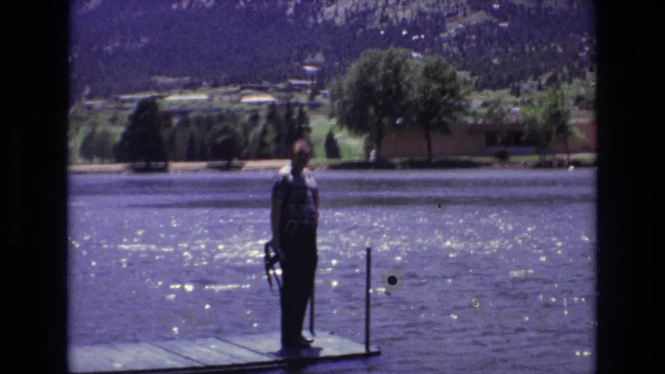 A man stands on a wooden dock holding a fishing rod beside a sunlit lake in Colorado Springs, Colorado, as supported by the clip metadata.