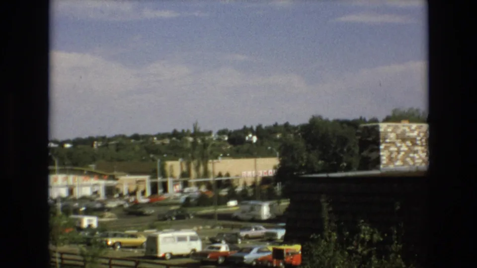 1973 Colorado Springs frame of cars and a white van near a low shopping center with Safeway signage and residential hillside beyond.