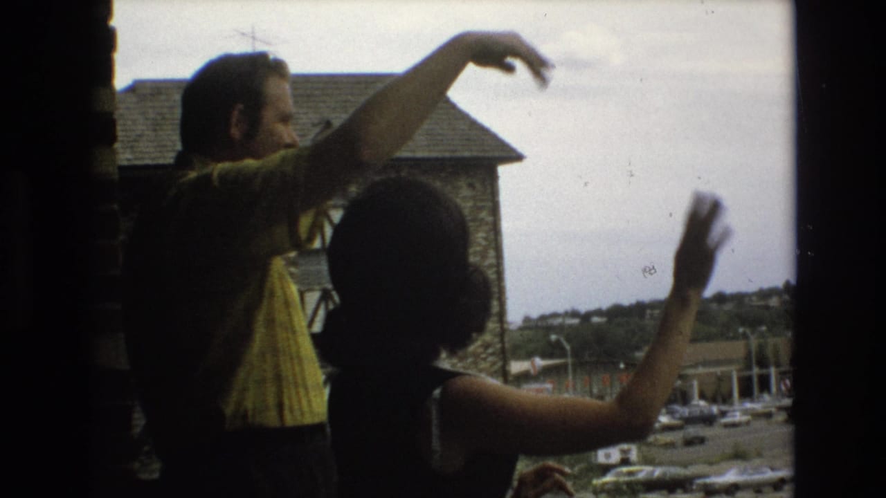 The man points outward while the woman waves near the window.