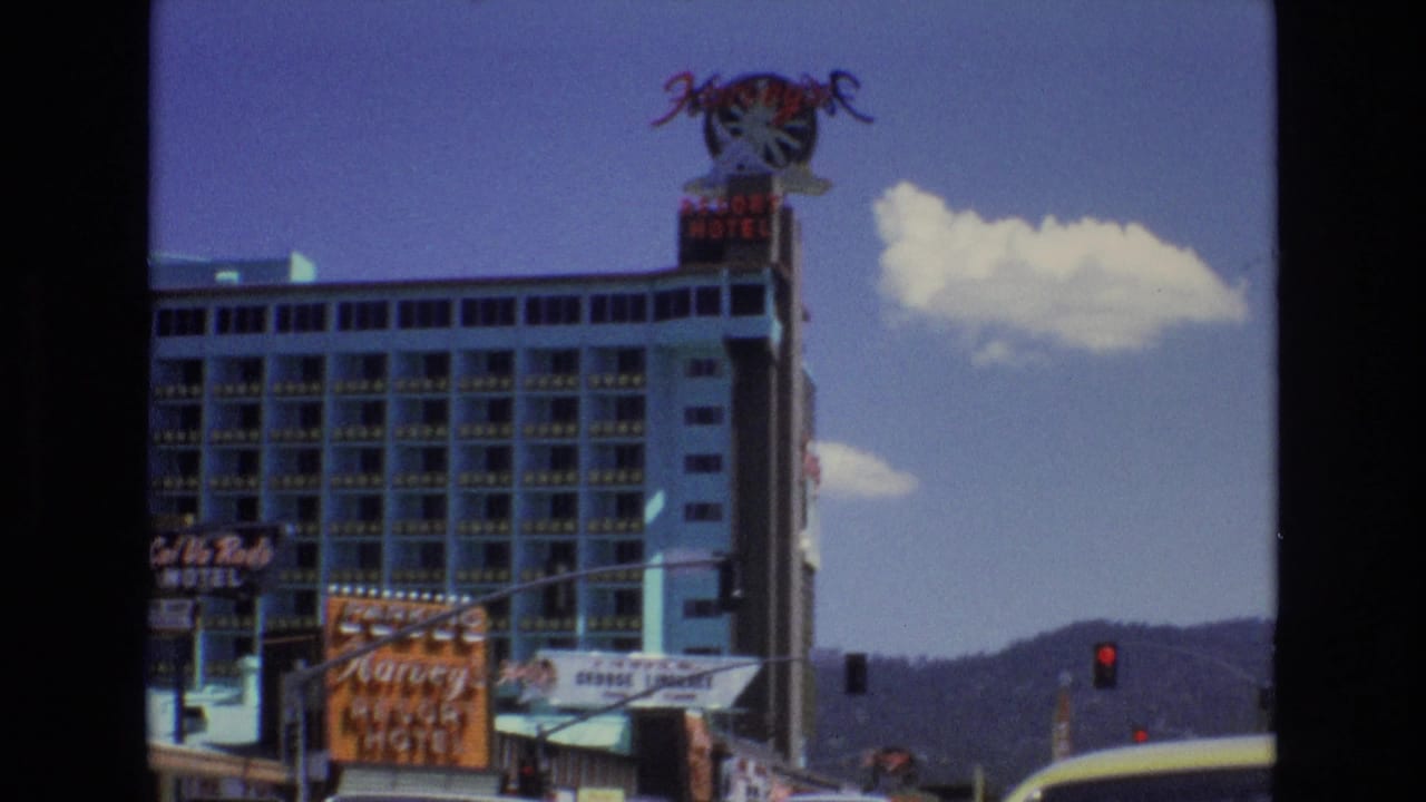 1973 Lake Tahoe, Nevada street view with Harvey's Resort Hotel signage, nearby motel signs, traffic signals, distant mountains, and bright clouds above the resort buildings.
