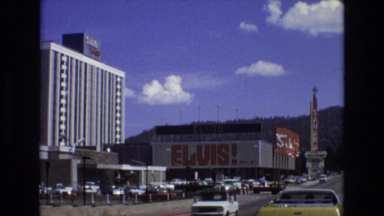 Busy street with Elvis building sign, hotel tower, cars, pedestrians, and Sahara sign.