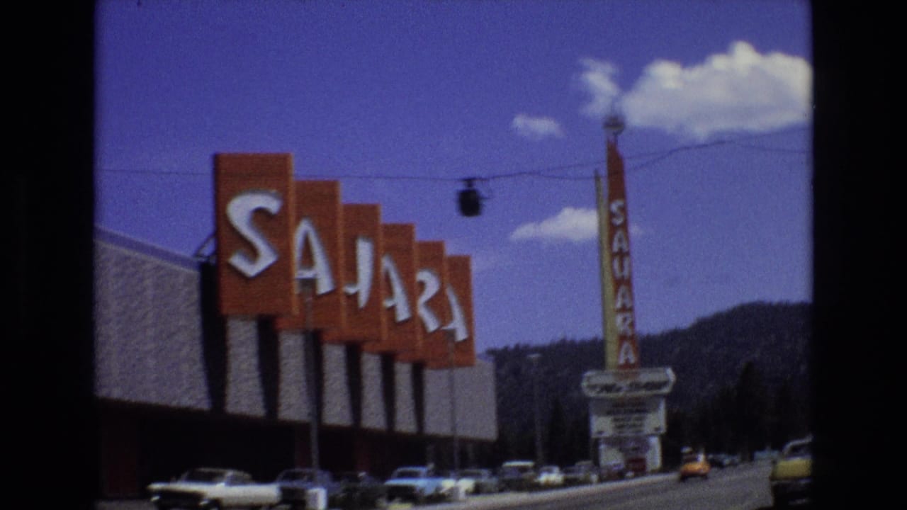 1973 Lake Tahoe, Nevada 8mm frame focused on the orange Sahara roadside lettering with cars below, the vertical tower sign, mountains, and overhead cable detail.
