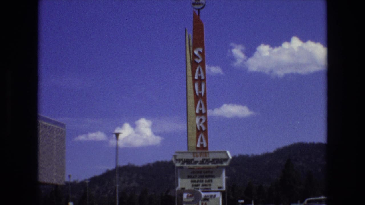 1973 Lake Tahoe, Nevada home-movie frame centered on the Sahara vertical sign and marquee, with a streetlight, mountain ridge, and blue sky behind it.