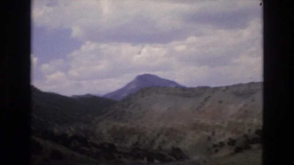 Rugged Lake Tahoe area mountain landscape under a cloudy sky, following the roadside attraction sequence in the 1973 8mm clip.