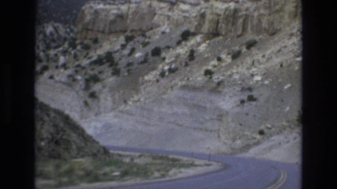 1973 8mm home-movie frame showing a winding asphalt road passing through dry rocky canyon terrain near Lake Tahoe, Nevada.