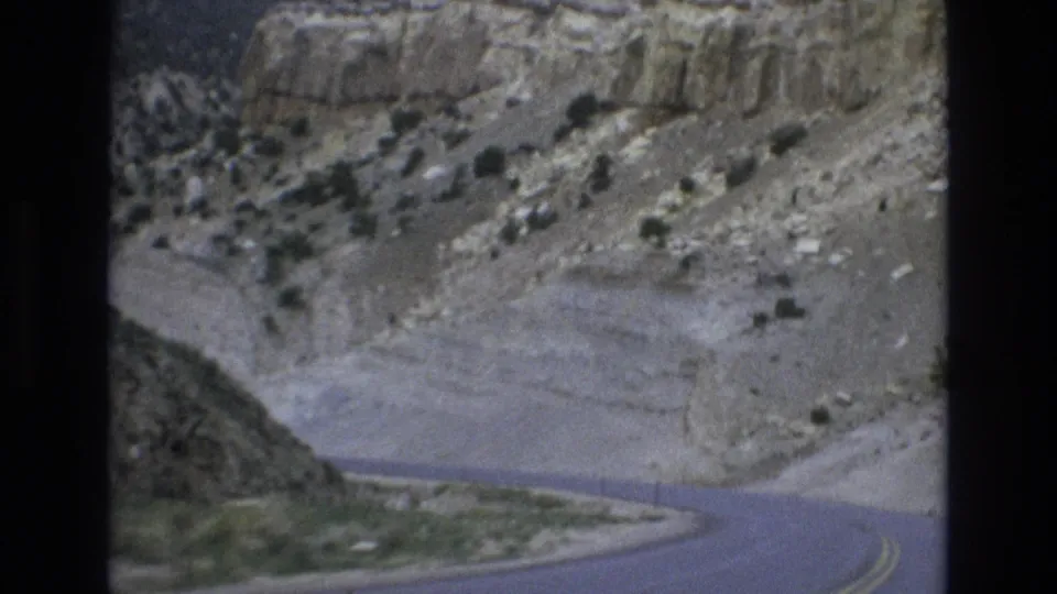 1973 8mm home-movie frame showing a winding asphalt road passing through dry rocky canyon terrain near Lake Tahoe, Nevada.