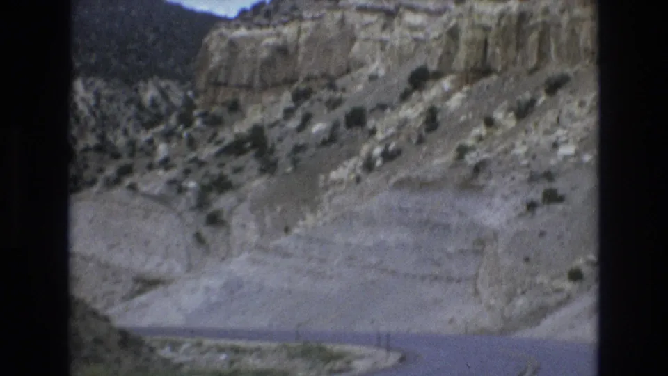 A winding road runs through arid canyon walls and scrubby slopes in this 1970s Lake Tahoe, Nevada travel frame.