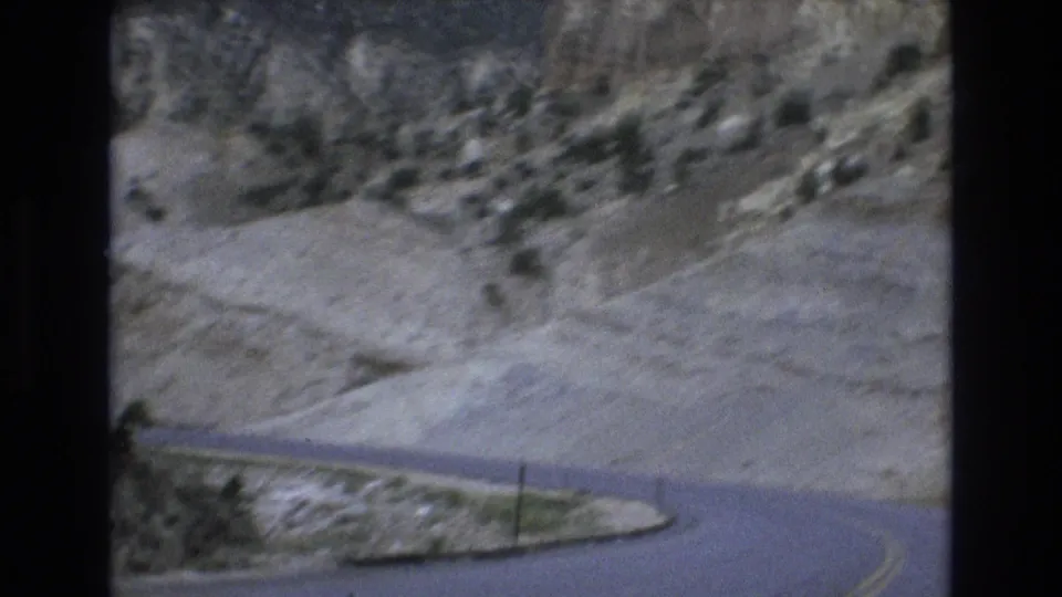 Handheld 8mm frame with motion blur showing a two-lane road curving through dry canyon slopes near Lake Tahoe, Nevada.