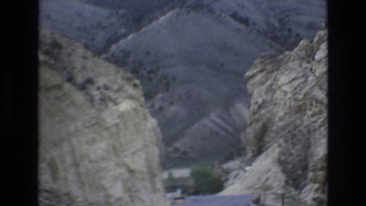 1973 Lake Tahoe, Nevada 8mm frame showing a road passing through a narrow rocky mountain cut with muted hills in the background.