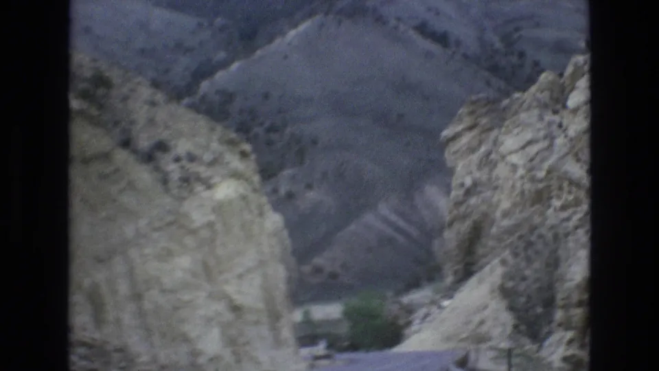 1973 Lake Tahoe, Nevada 8mm frame showing a road passing through a narrow rocky mountain cut with muted hills in the background.