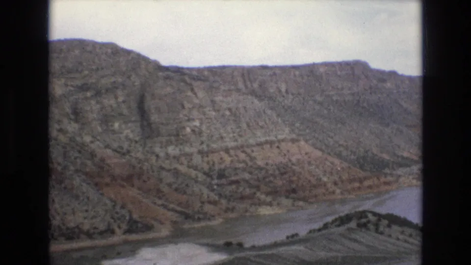 1973 8mm home-movie view of eroded Lake Tahoe, Nevada-area hillside terrain descending toward water, with sparse trees and muted color from the film scan.