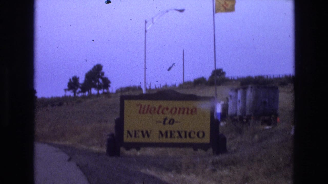 Welcome to New Mexico roadside sign beside a dry road landscape.