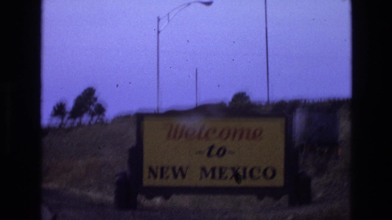 Welcome to New Mexico sign seen from the roadside at dusk or low light.