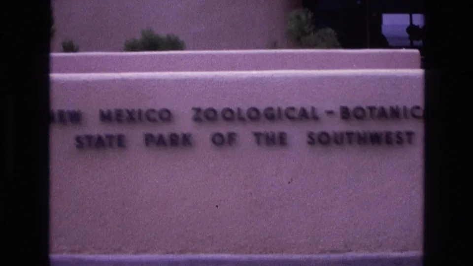 1973 New Mexico 8mm frame with a soft, cropped view of the engraved state park sign and pale building wall behind it.