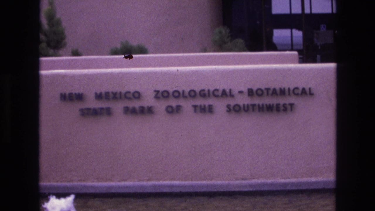 New Mexico Zoological-Botanical State Park sign on a stucco wall with a fountain below.
