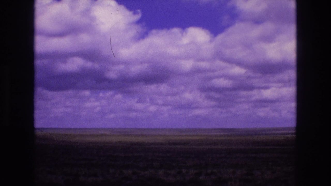 Distant plains and cloud-filled purple sky framed by dark vertical 8mm film borders.