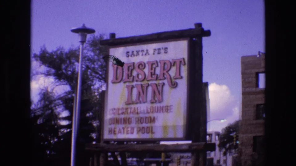 A clearer 1973 New Mexico view shows the Santa Fe's Desert Inn sign with cocktail lounge, dining room, and heated pool text beside trees and a nearby building edge.