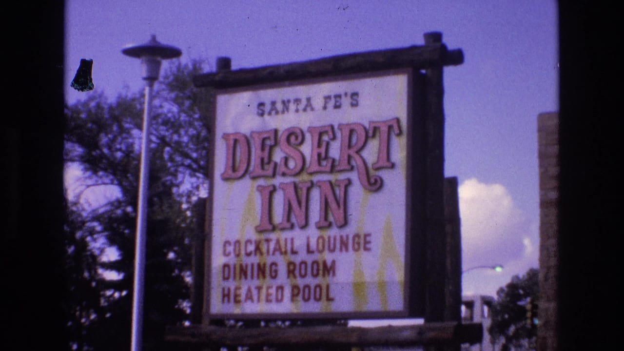 1973 home-movie frame from Santa Fe, New Mexico showing the Desert Inn roadside sign with cocktail lounge, dining room, and heated pool text, framed by trees and a street lamp.
