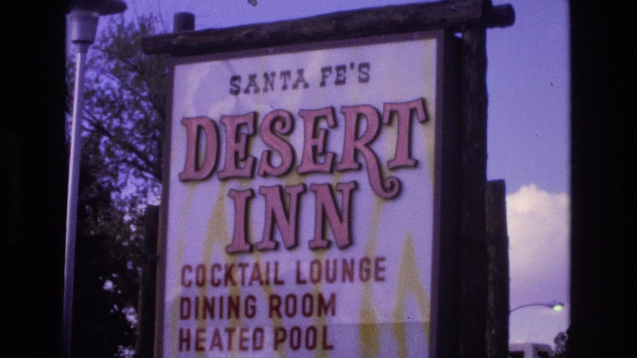 Close 1973 New Mexico view of the Santa Fe's Desert Inn sign framed by dark film edges, sky, tree branches, and a glimpse of a streetlight.