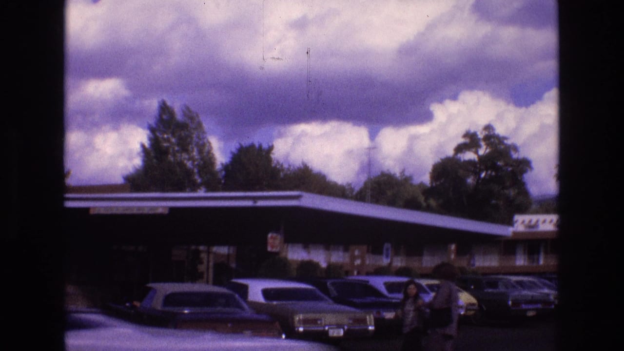 Motel parking lot with vintage cars and a person near the right side.