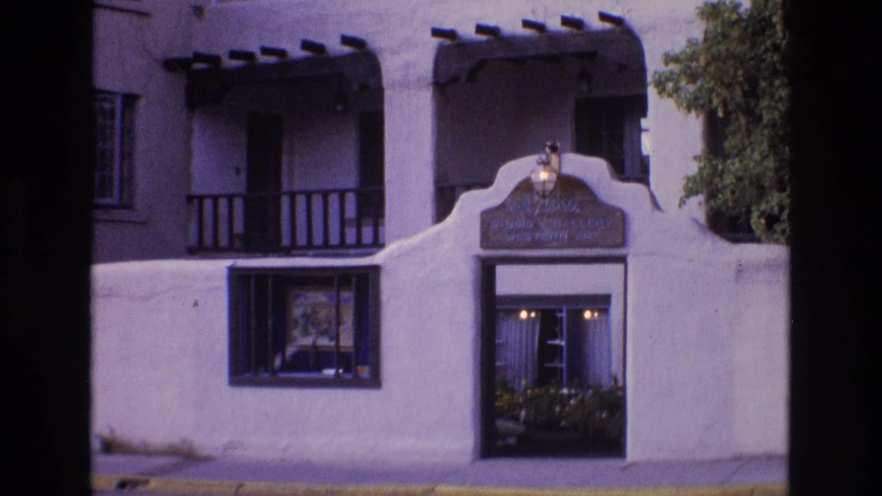 White stucco adobe-style building facade with balconies and a curved entry wall.