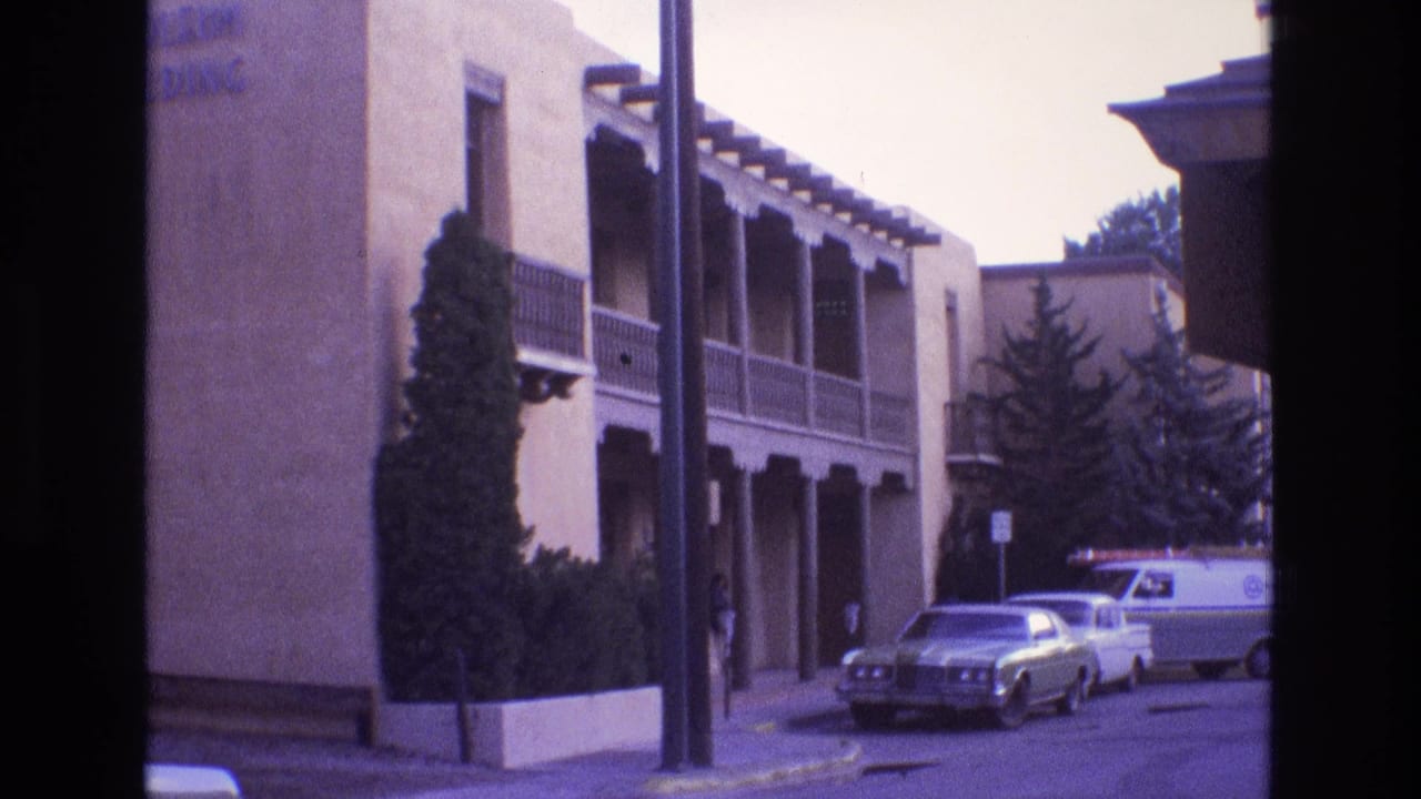 Similar street view with stucco building, balcony, parked cars, and a white van.