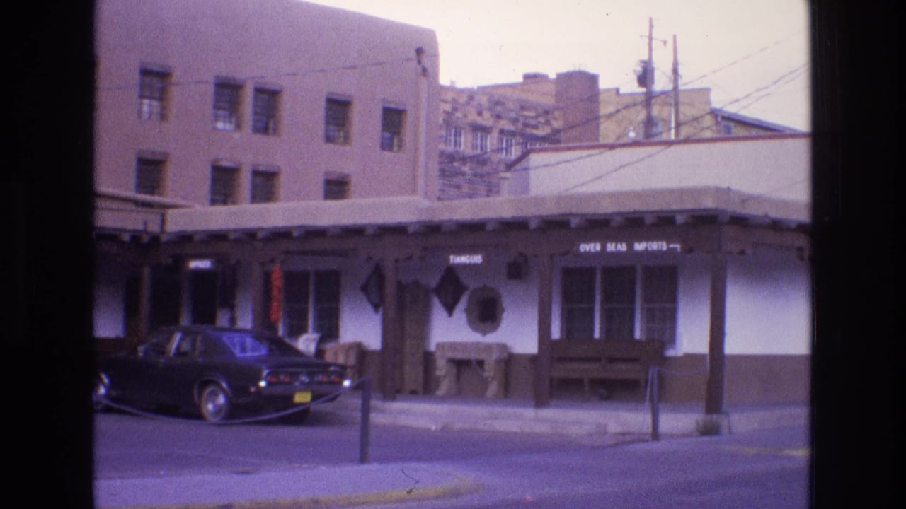 Covered storefront with signs and a dark car parked partly in front.