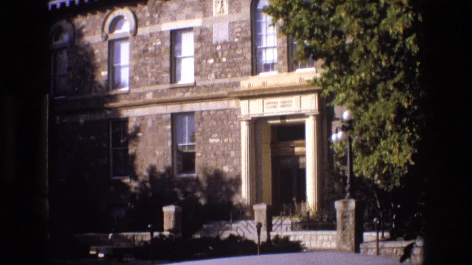 1973 New Mexico 8mm frame showing a stone United States Court House facade with a columned doorway, railings, windows, and partial tree shade.