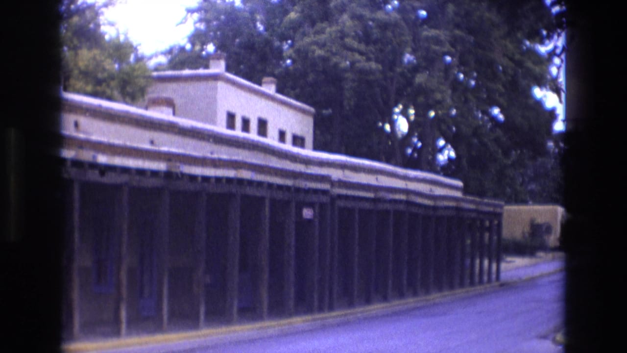 Long adobe-style building with covered posts along a quiet street.