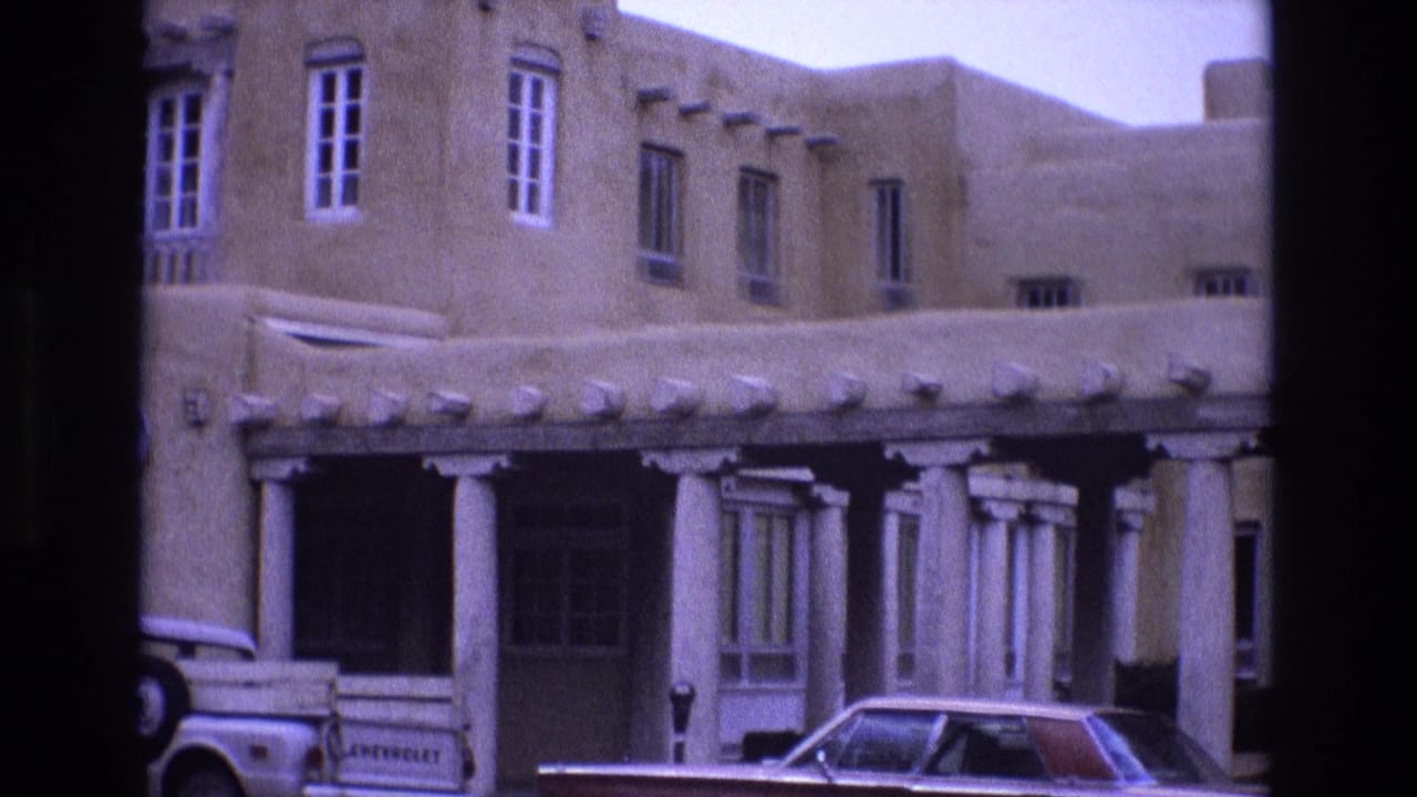Building entrance with white columns, parked car, and Chevrolet pickup nearby.
