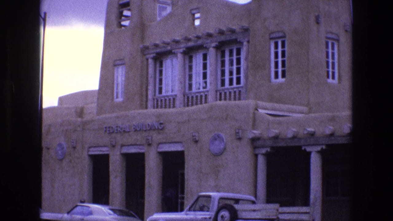 Adobe-style Federal Building facade with columns and parked cars along the street.