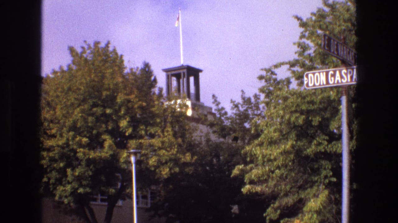 1973 New Mexico street-corner view with Don Gaspar signage, leafy trees, a small tower, and a flagpole visible above the roofline.