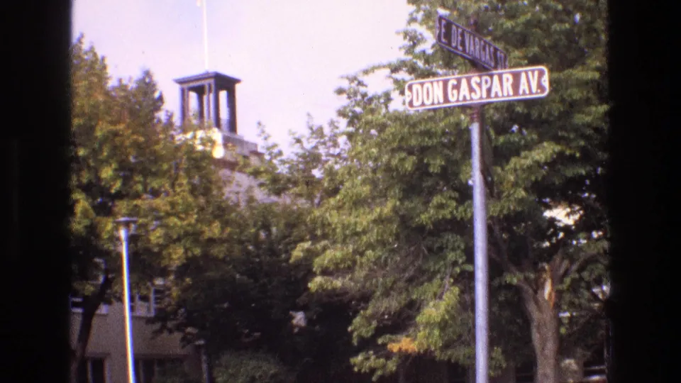 1973 New Mexico 8mm frame clearly showing Don Gaspar Avenue and E. De Vargas Street signs, with a small bell tower and tree-covered building behind them.