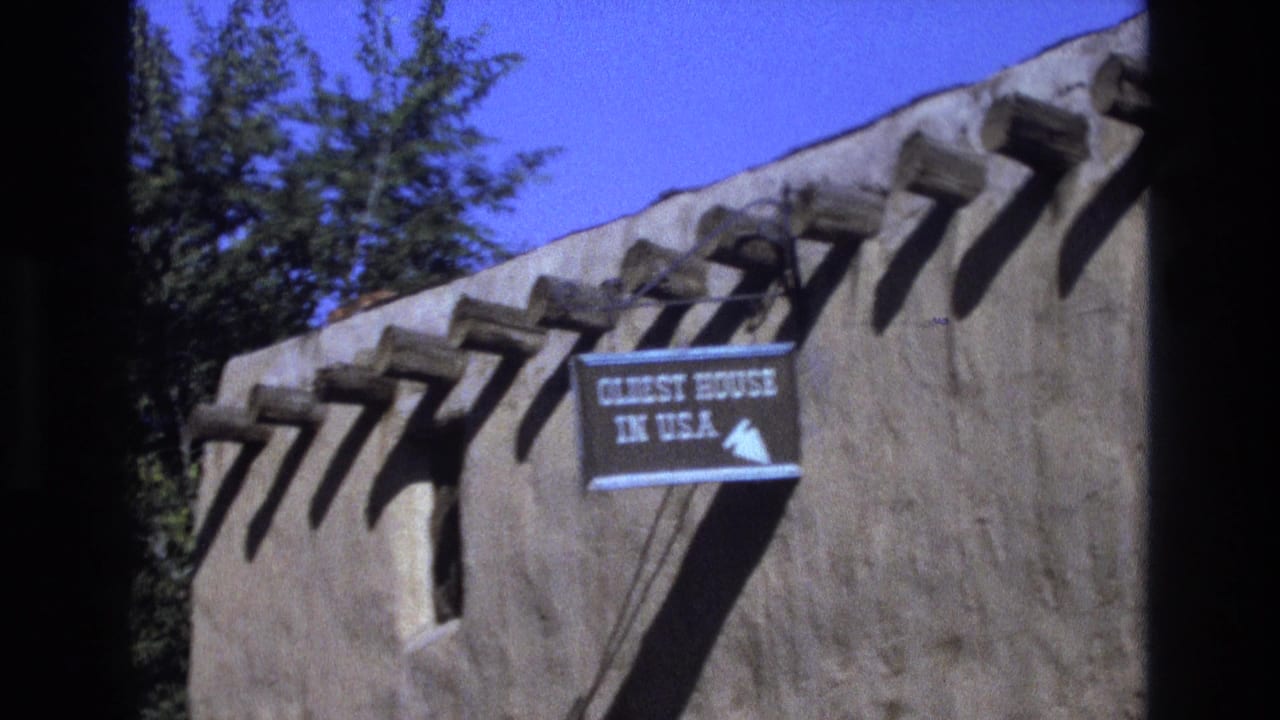 Adobe wall with wooden vigas and a blue sign reading “OLDEST HOUSE IN U.S.A.”