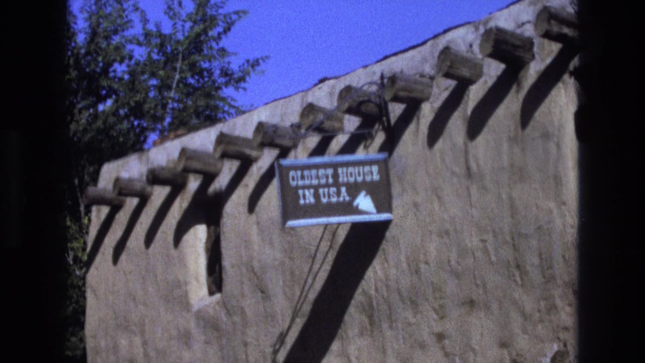 Adobe wall with an Oldest House in U.S.A. sign under bright daylight.