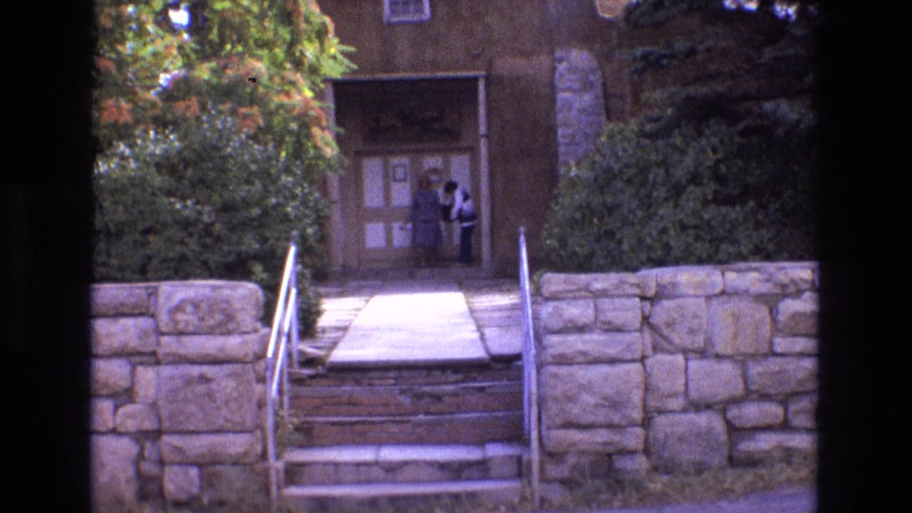 Stone steps and railings lead toward the San Miguel Chapel entrance with two women near the doorway.