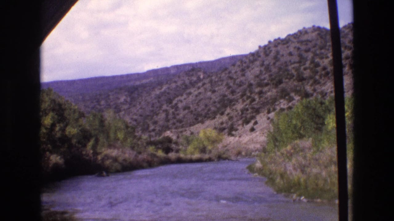 River bend, trees, and rugged hills framed by a vehicle window.