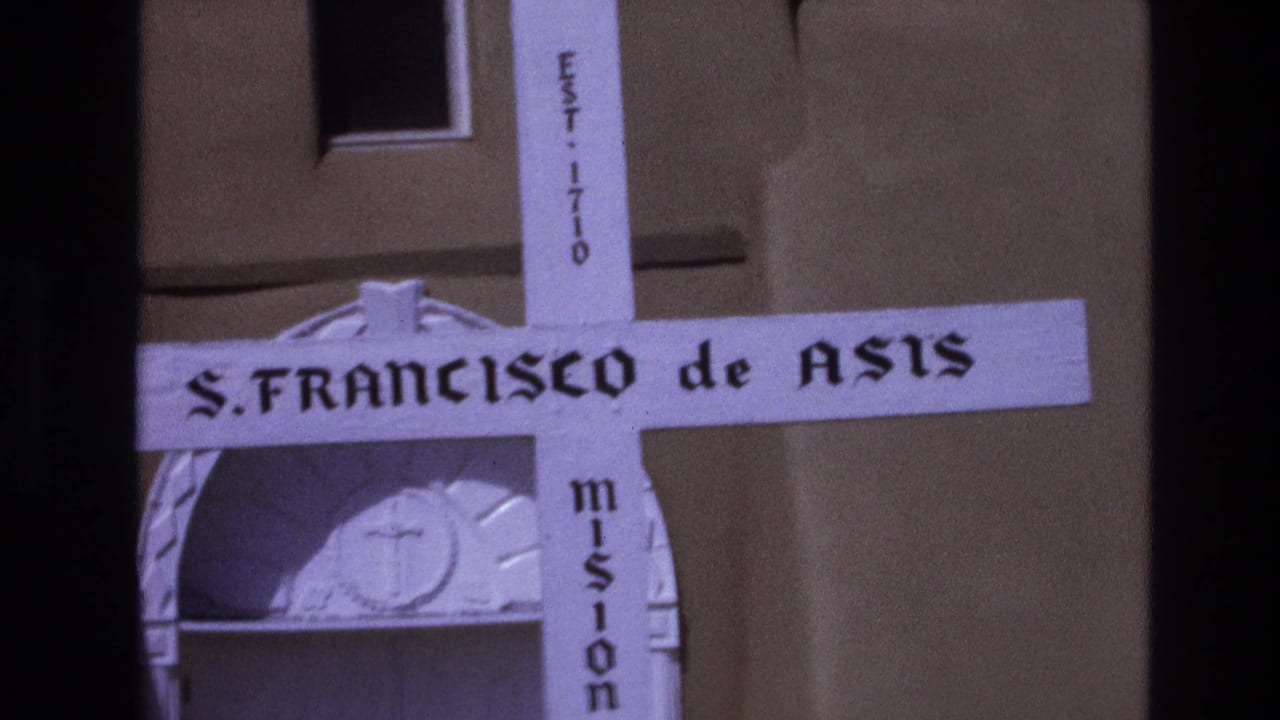 Close view of a white mission cross sign reading S. FRANCISCO de ASIS.
