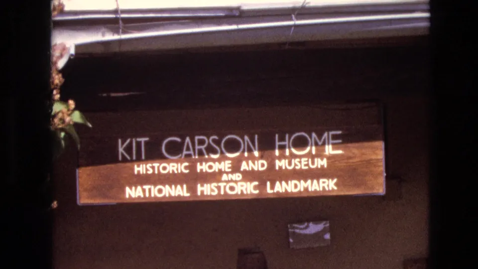 1973 New Mexico 8mm frame with a closer handheld view of the Kit Carson Home historic home and museum sign and its National Historic Landmark wording.
