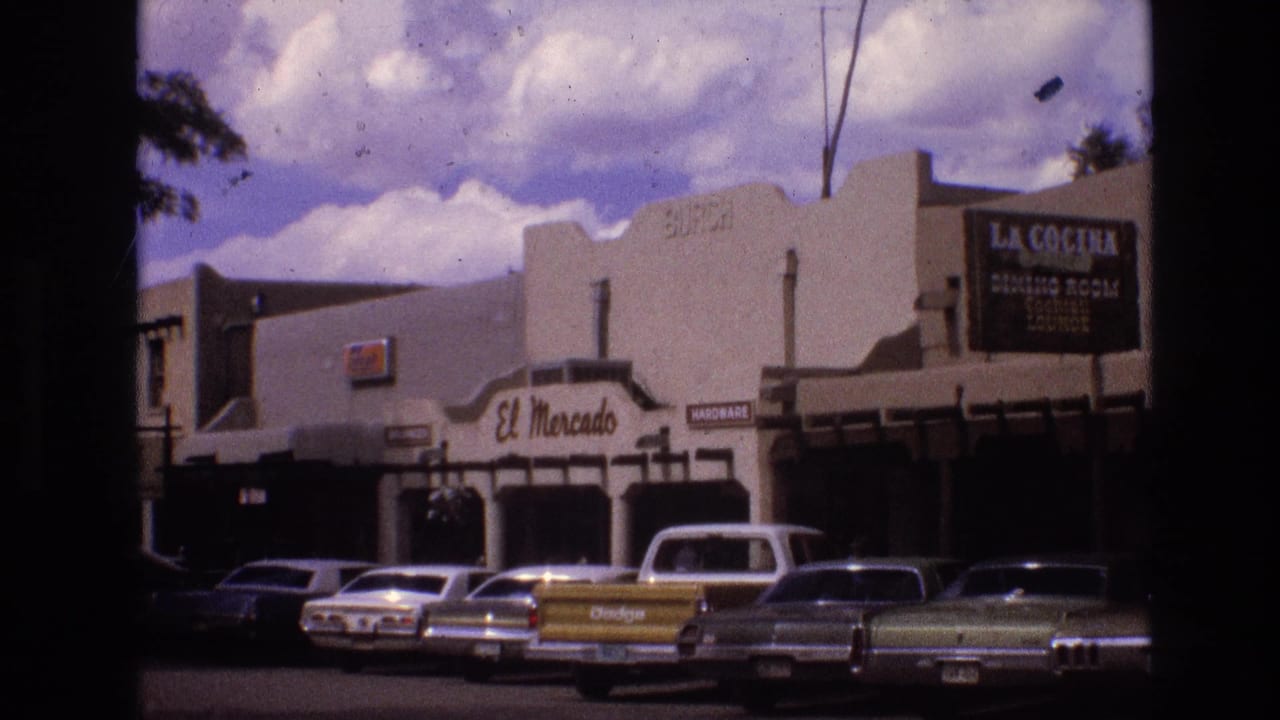 Parked cars and a yellow pickup outside El Mercado and La Cocina storefronts.