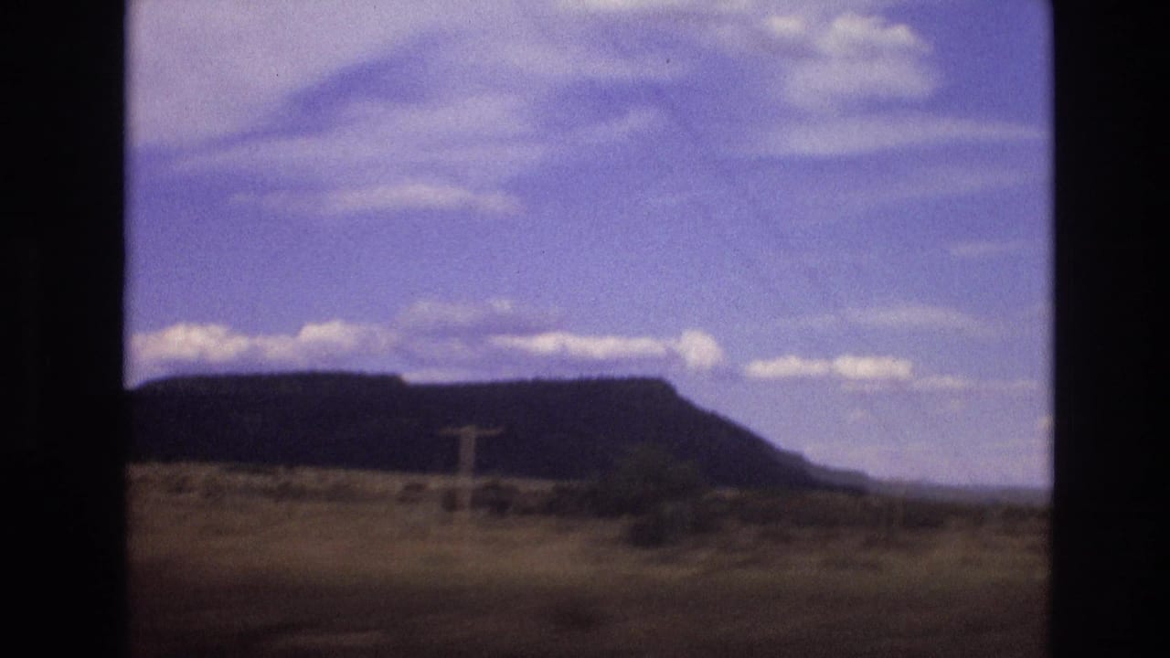 Flat-topped mesa across dry open ground beneath a blue sky.