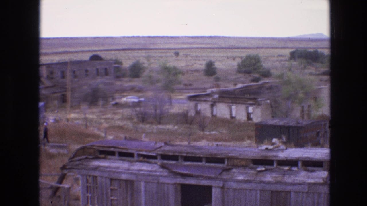 Abandoned structures and open plain with a distant figure near the ruins.