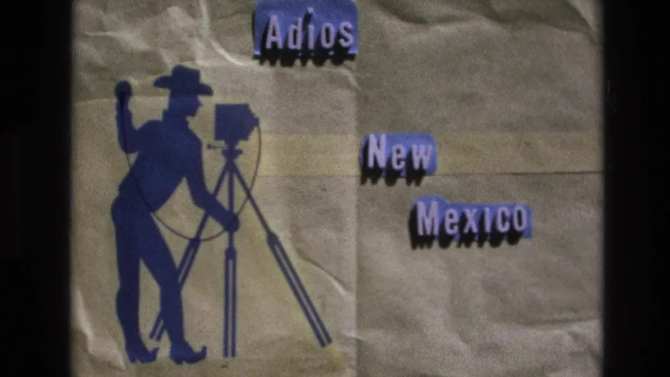 1973 8mm home-movie frame showing an "Adios New Mexico" title card, with a stylized camera operator silhouette and visible film softness and fading.