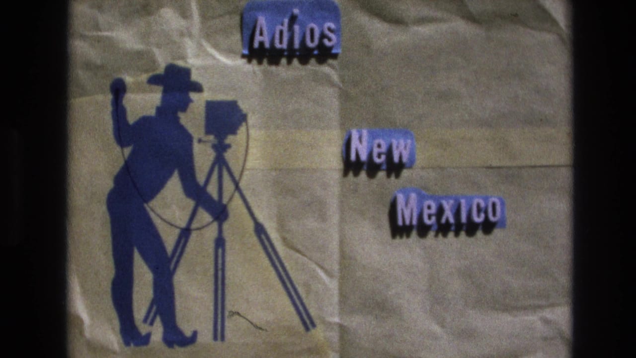 1973 New Mexico home-movie title card on textured brown paper, showing a blue cowboy photographer silhouette beside a tripod-mounted camera and cut-out words reading "Adios New Mexico."